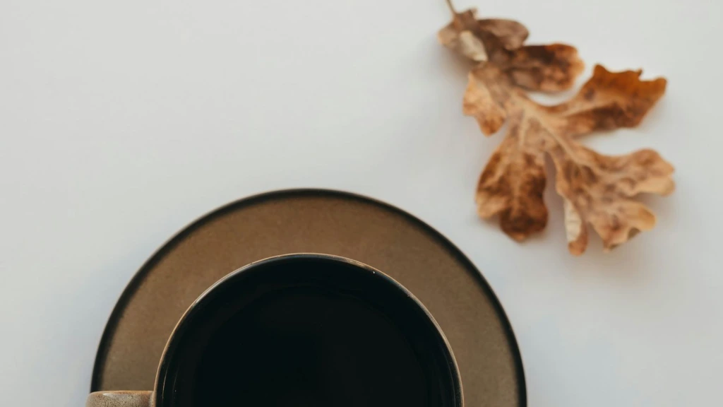 A cup of coffee with a dried oak leaf A cup of coffee with an oak leaf